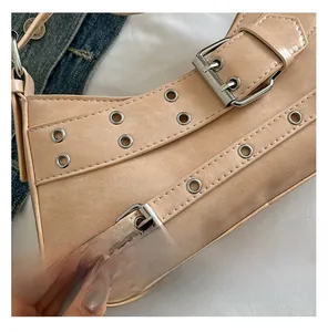 Gros plan d'un sac baguette en daim rose avec œillets métalliques et boucles de ceinture