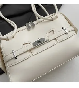 Detailed view of cream leather handbag with silver twist lock and strap accents