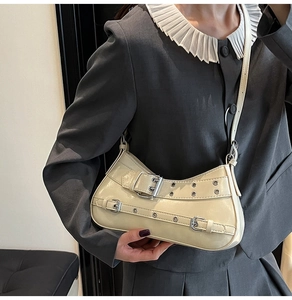 Détail d'un sac à bandoulière en cuir verni blanc crème avec boucle en métal et rivets