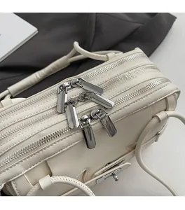 Close-up of triple silver zippers and premium woven leather texture on cream handbag