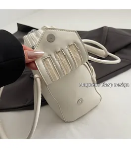 Detail view of the magnetic buckle design and triple zipper decor on a cream leather tote