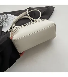 Close-up of the flat bottom and metal buckles on a cream leather shoulder bag