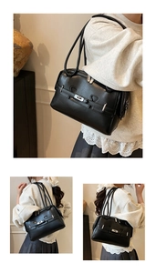 Detail of black underarm bag with silver buckle and multi-layer zipper compartments
