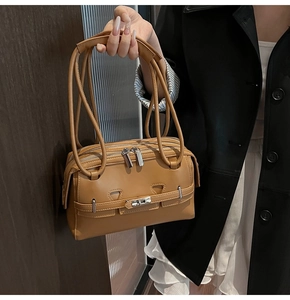 Detail of caramel underarm bag with three silver zippers and unique long straps