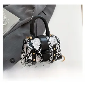 Detail of snake print mini bag with gold rivets and beaded chain on office desk