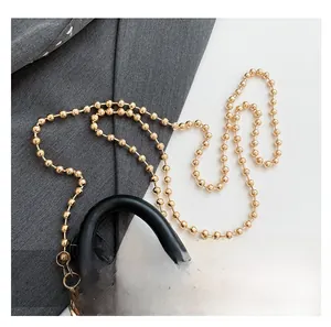 Detail of elegant gold beaded chain strap and snakeskin texture on leather handbag