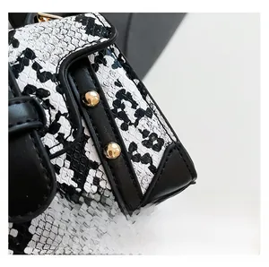 Detail view of black and white snakeskin texture with gold metal studs on a mini bag