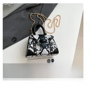 Mini trapezoid handbag in snake skin pattern with gold studs and chain strap detail