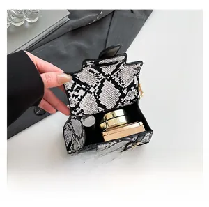 Detailed interior of a snake-pattern mini handbag showing capacity for cosmetics and accessories