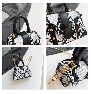 Detail of mini black and white snakeskin pattern bag with gold rivets and bead chain