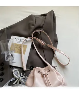 Détail de sac seau rose clair avec cordon de serrage et bandoulière à boucle métallique
