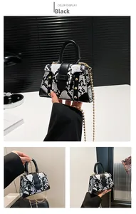 Close-up of black and white snakeskin handbag with gold studs and metal chain strap