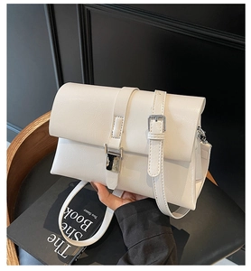 Macro shot of white leather fold-over handbag with textured pleats and silver metal buckle