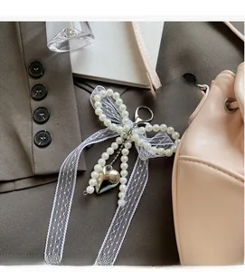 Charm nœud en perles avec pendentif cœur et ruban dentelle sur un sac seau rose