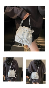 Détail du sac seau gris clair brillant avec œillets métalliques et nœud en perles