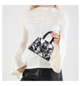 Close-up of mini snakeskin handbag with black leather trim and gold rivet detailing