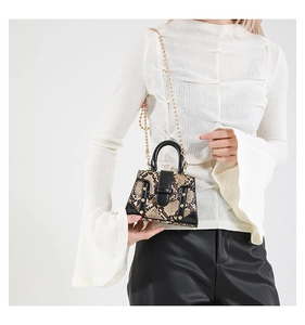 Detail of snake print leather handbag with gold beaded chain and elegant metal rivets