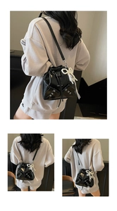 Détail du sac seau noir plissé avec œillets métalliques et breloque en perles et dentelle