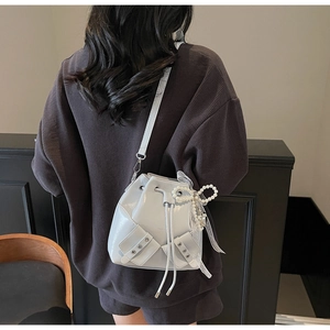 Détail du sac seau en cuir gris brillant avec un nœud en perles et un ruban décoratif