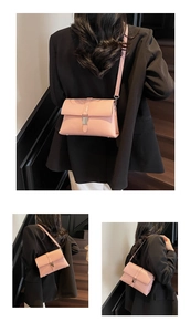 Pale pink rectangular shoulder bag with metal buckle shown on model in a staircase setting
