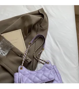 Detail of lavender quilted shoulder bag with golden woven chain on a lifestyle background