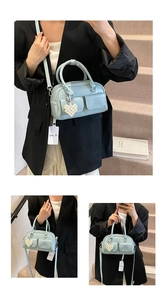 Detail of light blue Boston bag with dual pockets and elegant pearl heart charm
