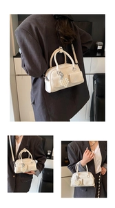 Detail showing cream PU leather Boston bag with pearl heart charm and crossbody strap