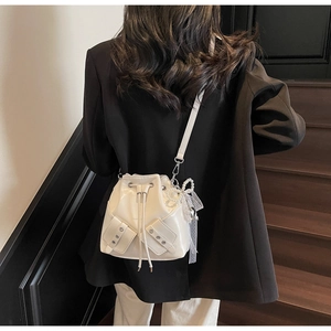 Vue détaillée du sac seau blanc en cuir verni avec nœud en dentelle porté par un mannequin