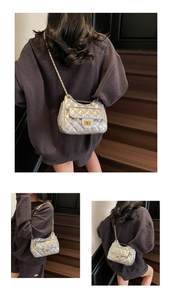 Detail view of silver quilted chain bag featuring metallic finish and gold turn-lock closure