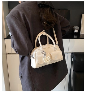 Detail of cream white Boston bag with pearl heart pendant and double front pockets