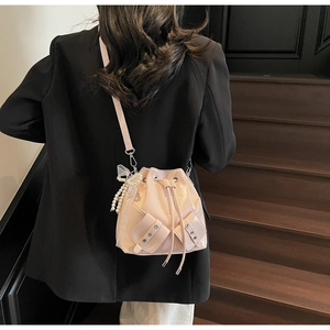 Sac seau rose avec breloque nœud en perles et cordon de serrage porté par un mannequin