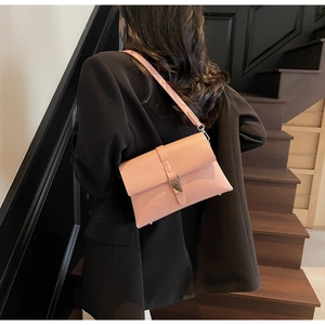 Pink oily leather crossbody bag with silver buckle worn over a black blazer