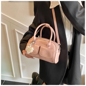 Detail of pink glossy boston bag with pearl heart charm and front pocket design