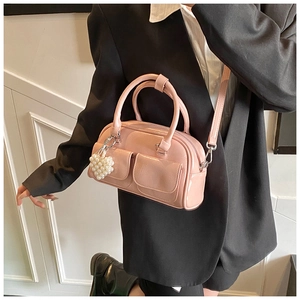 Pink patent leather Boston bag with pearl heart charm shown from side view on model