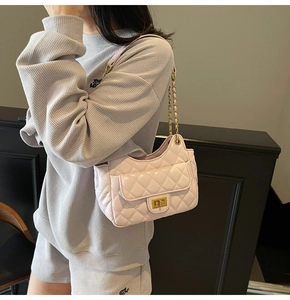 Detail view of light pink quilted crossbody bag with gold chain strap and metal lock