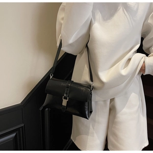 Detail of minimalist black oil wax leather underarm bag with silver buckle and sleek texture