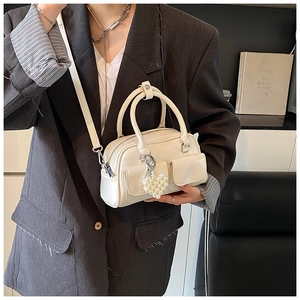 White leather Boston bag with heart pearl charm shown on model in a modern interior
