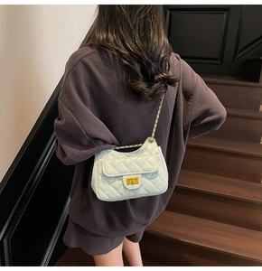 Detail of light mint green quilted shoulder bag featuring gold twist lock and chain strap