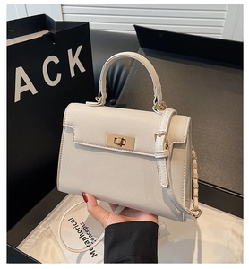 Detail showing cream leather texture and gold metal twist lock on the mini Kelly handbag