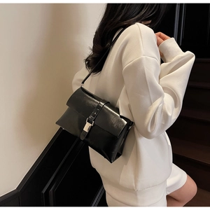Detailed view of the silver square metal buckle on a black glossy leather shoulder bag
