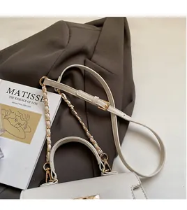 Detail of white textured leather handbag with gold chain strap beside a brown blazer