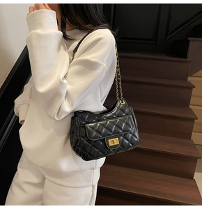 Detailed close-up of the black quilted texture and golden chain strap on shoulder bag