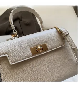 Detail of cream-colored cross-grain leather handbag with elegant gold rectangular twist lock
