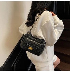 Close-up of quilted black leather texture and gold chain strap on shoulder bag