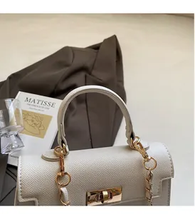 Close-up of white crossbody bag with cross-grain leather and golden turn-lock