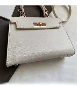 Close-up of a cream leather Kelly bag featuring fine grain texture and gold twist lock