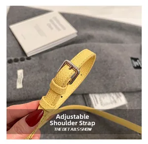Détail de la bandoulière réglable avec boucle argentée sur le sac en cuir litchi jaune