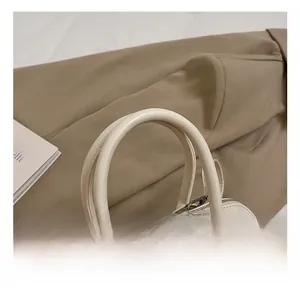 Détail du sac à main beige minimaliste montrant la texture cuir et les finitions argent