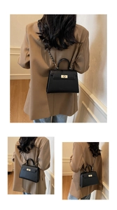 Detail of black lychee grain leather Kelly bag with gold buckle and chain strap