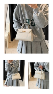 Detail of cream trapezoid handbag featuring gold turn-lock closure and leather texture